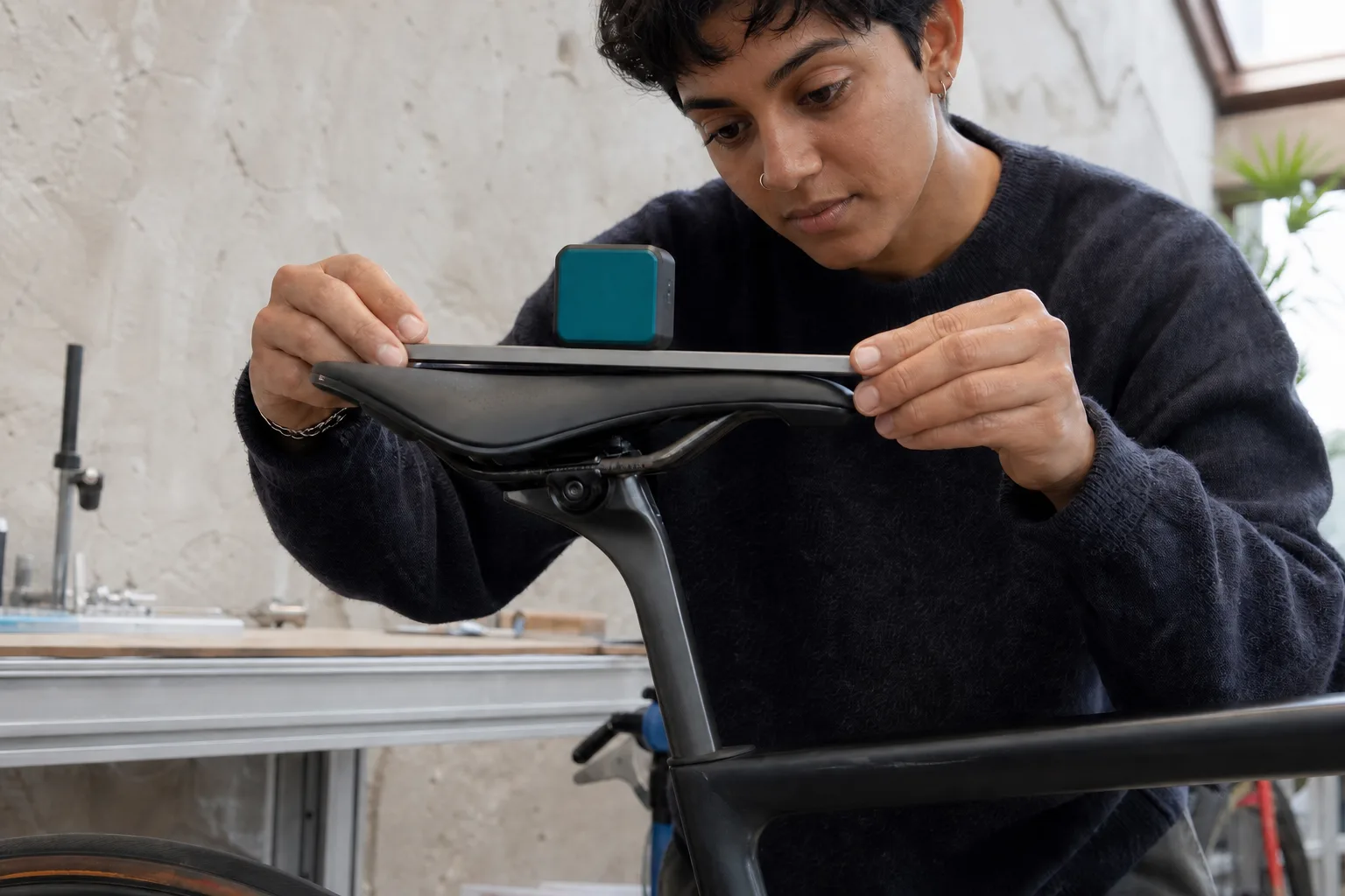 A digital angle tool aligned to the usable centre surface of a bicycle saddle in a bright workshop